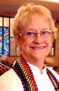 portrait of Betsy Schwarzentraub wearing a rainbow colored scarf or stole