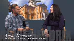 Poet Annie Hendrix and host Dan Araujo sitting on side-by-side chairs on the set of his Auburn Community Television series called "Work in Progress"